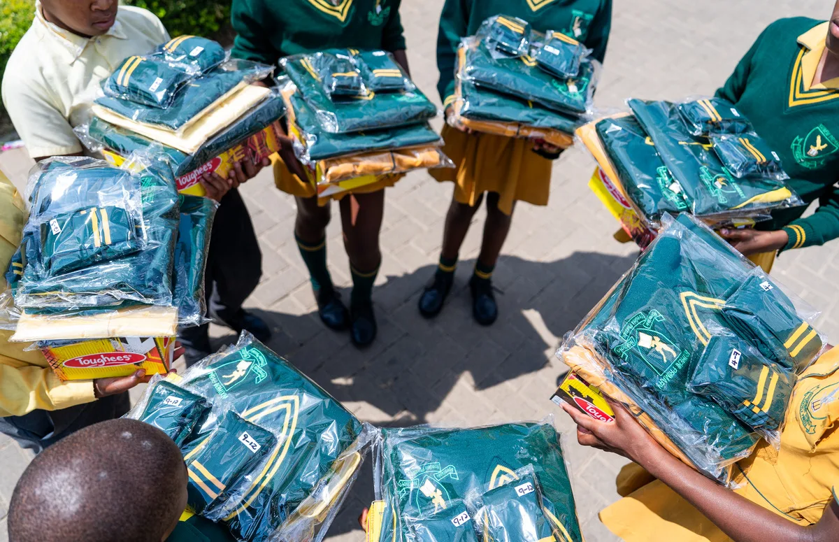 Inxiweni Primary School learners holding their wrapped green and gold school uniforms