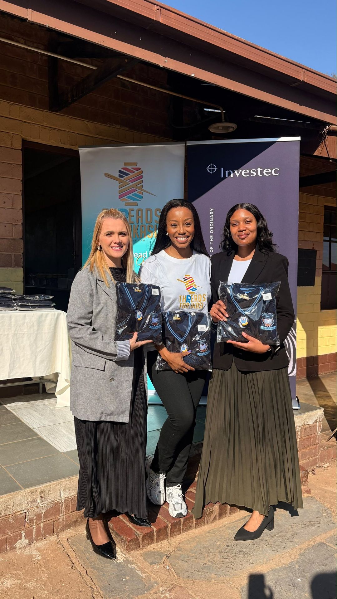Representatives from Threads for iKasi Foundation and Investec holding Sindawonye Primary School jerseys at the handover