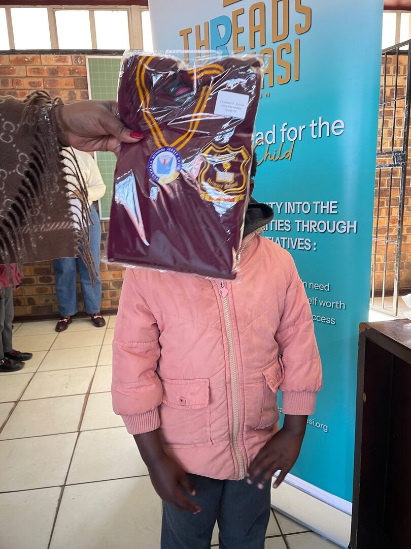 A Thuthuka Primary School learner receiving a labelled school jersey at the Threads for iKasi banner