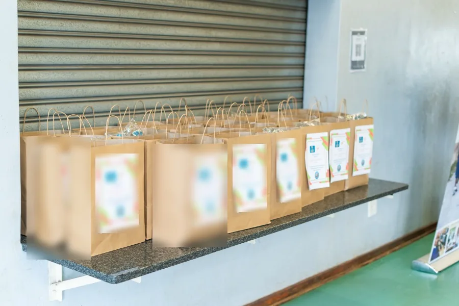 Uniform bags, each labelled for a named learner, lined up before the handover at Tshepisa Primary School