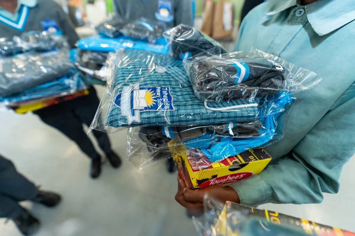 A learner at Tshepisa Primary School holding a full school uniform received at the handover